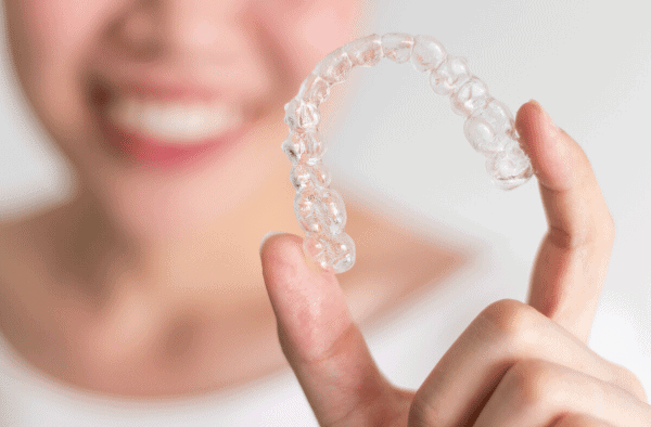 Woman with Invisalign Women smiling holding Invisalign