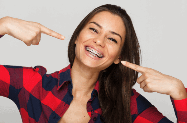 Woman with Braces Woman with Braces Smiling and pointing to her teeth