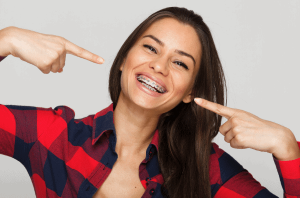 Woman with Braces Smiling and pointing to her teeth