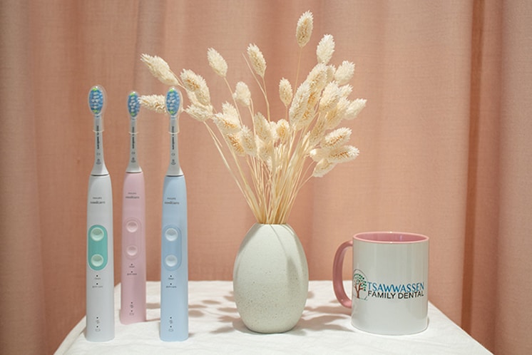 Three electric toothbrushes on a table next to Tsawwassen mug and decor