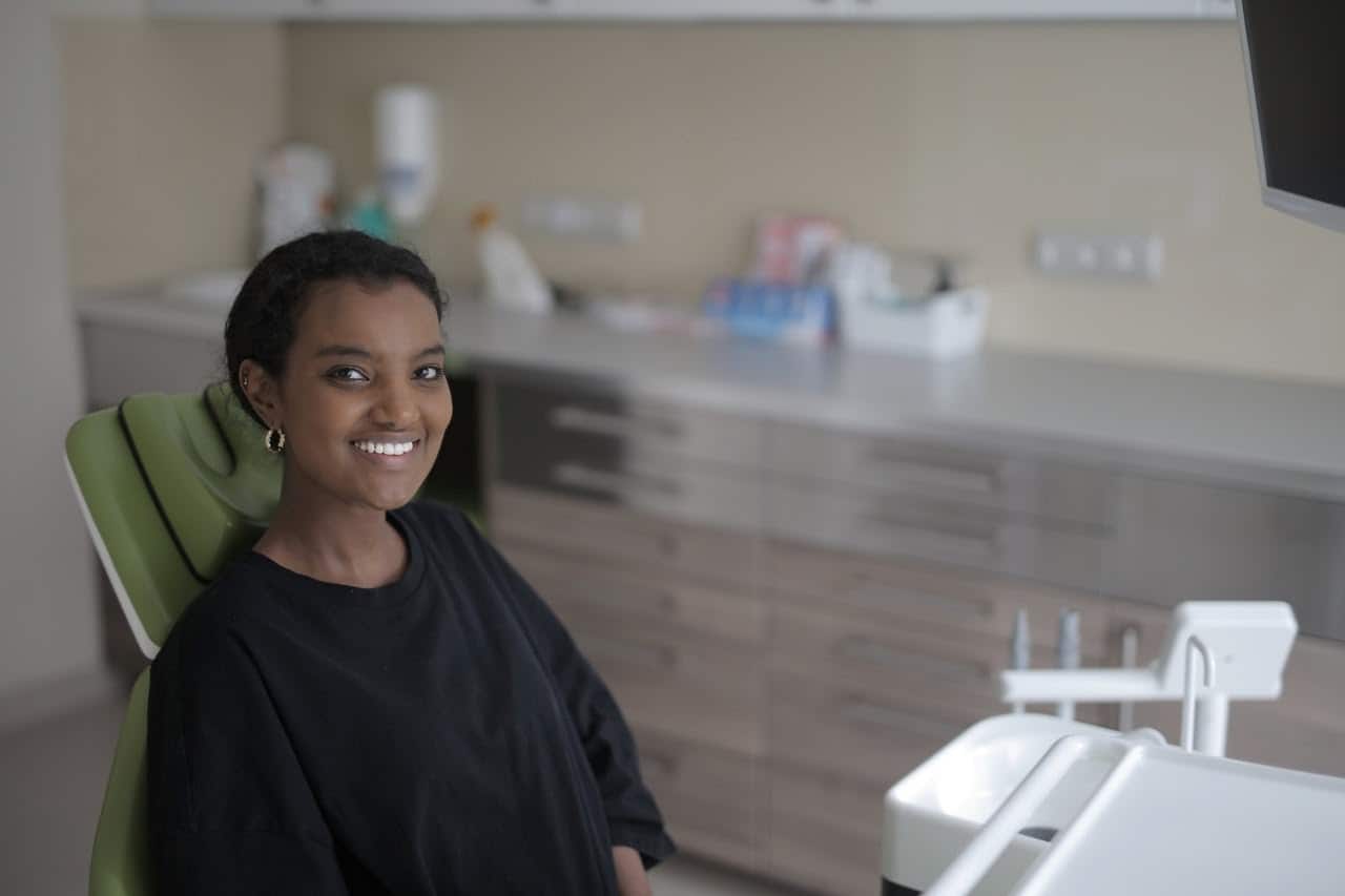 smiling-young-ethnic-female-patient-in-dental-chair-in Smiling woman sitting in a dental chair.