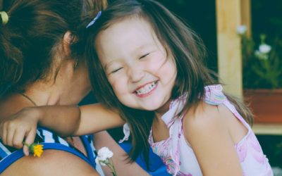 Toddler smiling in her mother's arms.