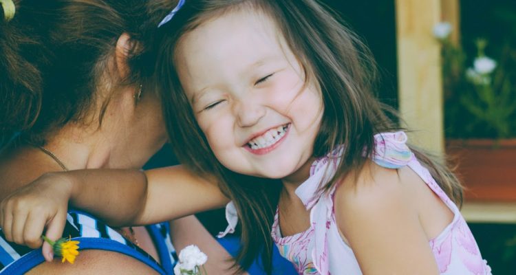 Toddler smiling in her mother's arms.