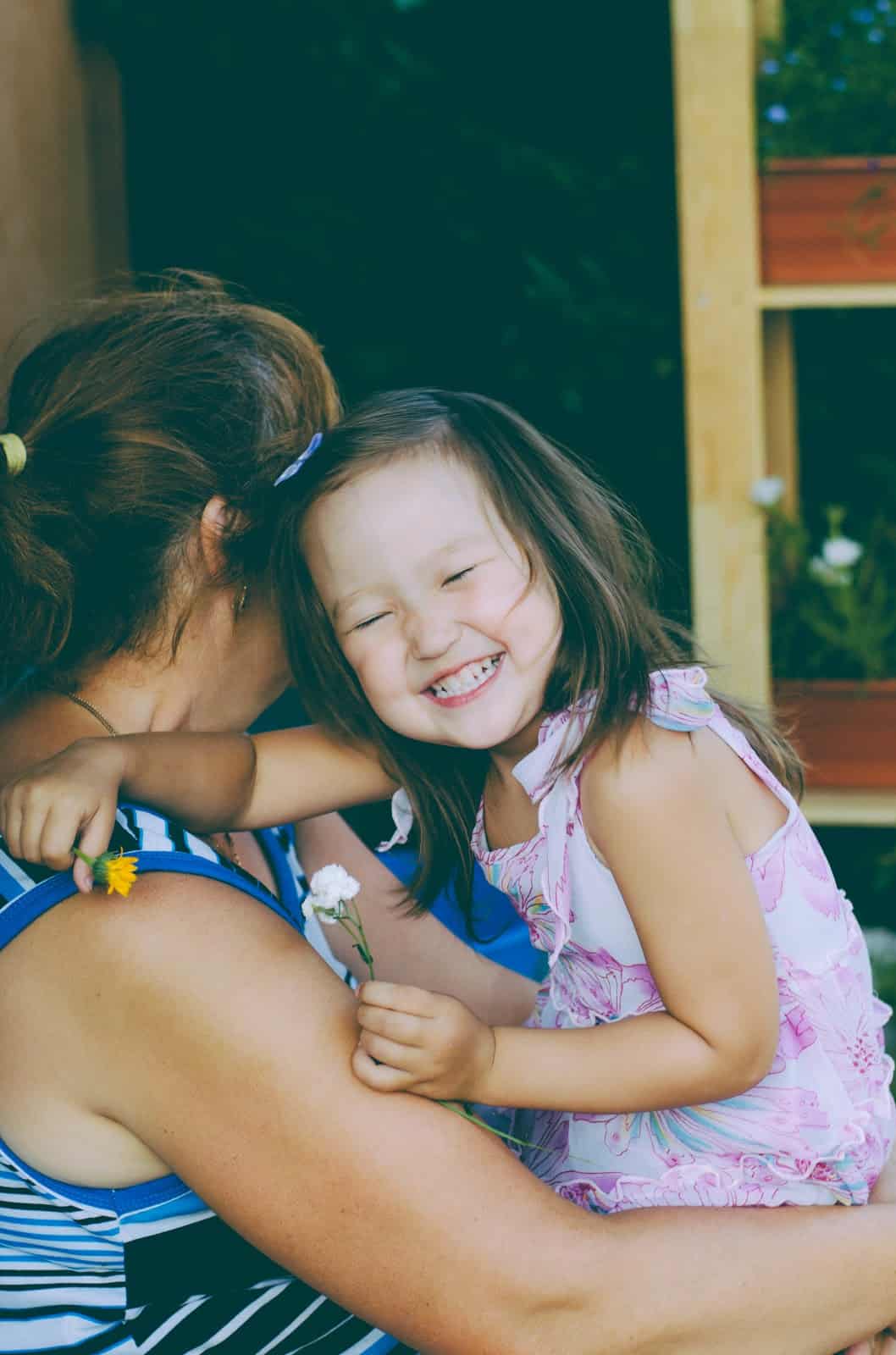 Toddler smiling in her mother's arms.