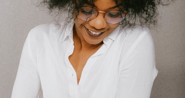 Smiling woman wearing glasses looking down at her paperwork.