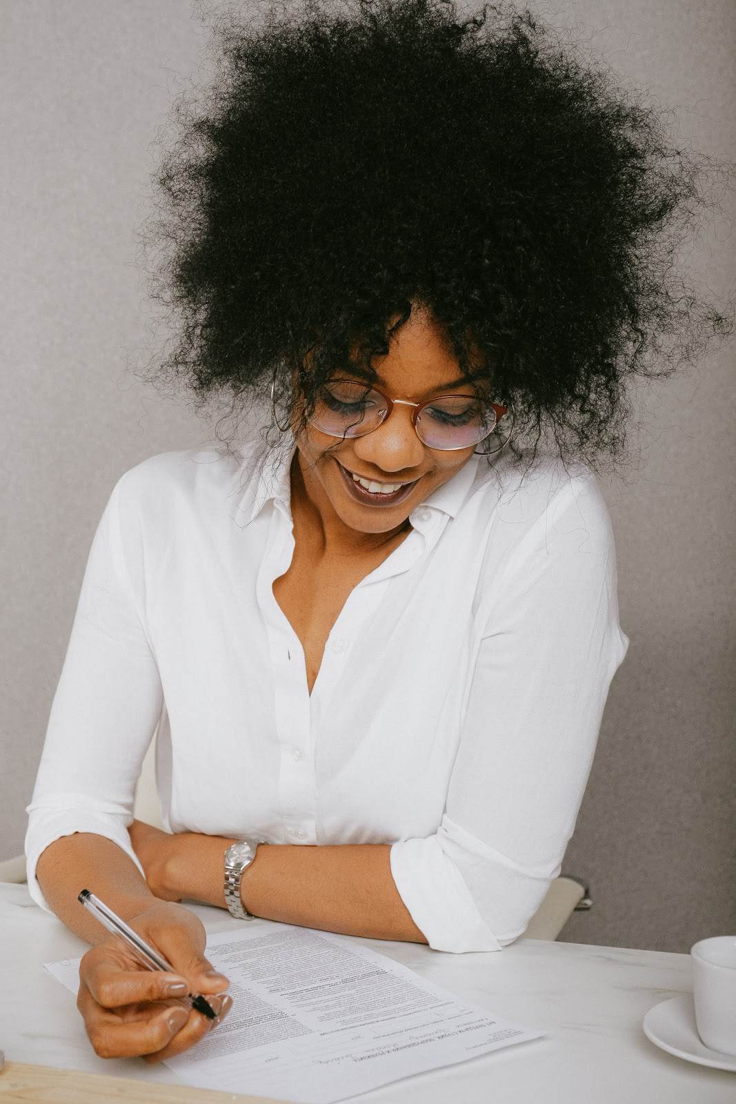 Smiling woman wearing glasses looking down at her paperwork.