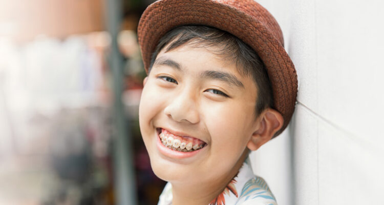 Smiling teenager with braces wearing a hat.