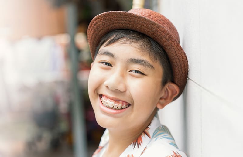 Smiling teenager with braces wearing a hat.