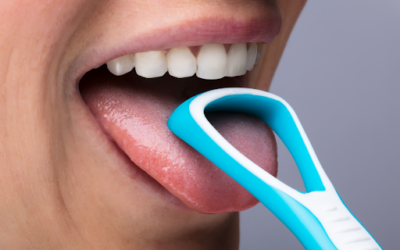 A person using a plastic scraper to clean their tongue.