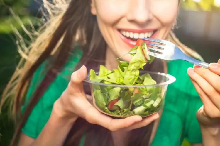 A picture of a woman eating salad after a dental filling